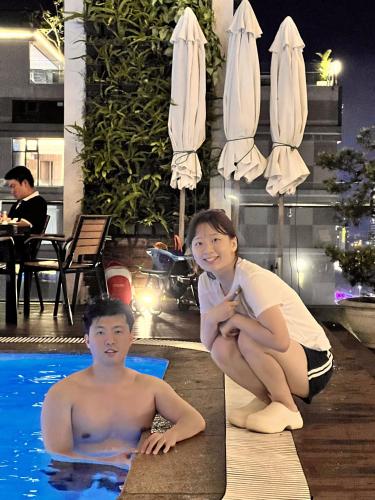 a man and a woman sitting next to a swimming pool at Diamond Sea Hotel in Da Nang