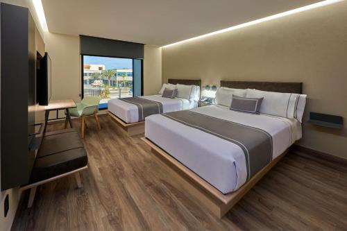 Habitación de hotel con 2 camas y TV de pantalla plana. en City Express Plus by Marriott Mazatlan en Mazatlán
