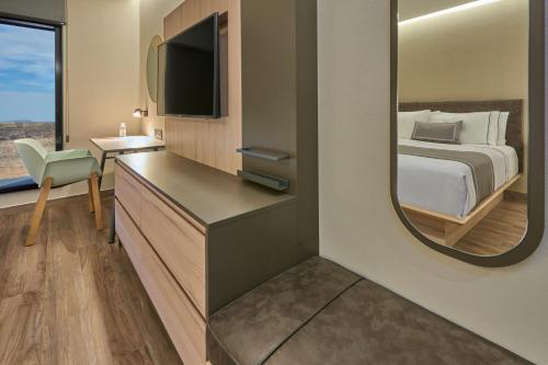 a hotel room with a bed and a mirror at City Express Plus by Marriott Mazatlan in Mazatlán