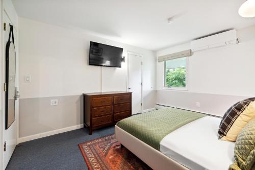 a bedroom with a bed and a tv on the wall at Mountaineer Inn in West Dover