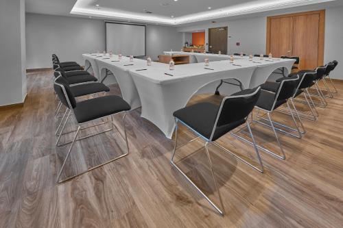 a conference room with a long white table and chairs at City Express Plus by Marriott Mazatlan in Mazatlán