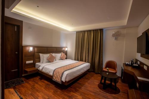 a hotel room with a large bed and a desk at Golden Fortune Hotel in Bangalore