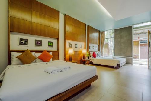 a bedroom with two beds and a large window at Nana Resort Kaeng Krachan - SHA Plus Certified in Kaeng Krachan