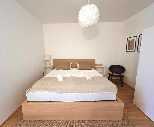 Un dormitorio con una cama con sábanas blancas y una lámpara de araña. en Gemütliche Wohnung mit Flair und Natur pur, en Viena