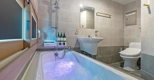 uma casa de banho com uma banheira com um lavatório e um WC em The Bay Hotel and Pool Villa em Suncheon