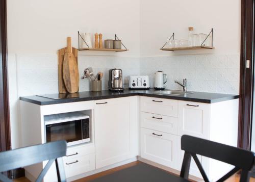 a kitchen with white cabinets and a black counter top at The Bower Mudgee in Mudgee