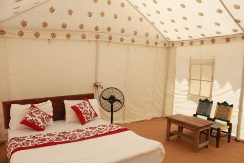 a bedroom with a bed and a table and chairs at Hindustan Desert Camp in Kūri