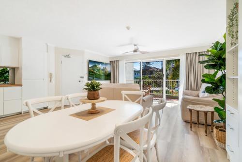 comedor y sala de estar con mesa blanca y sillas en Markham Court, en Gold Coast