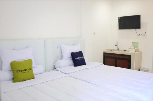 een slaapkamer met een wit bed met 2 kussens bij Urbanview Hotel Eropa Maros Near Sultan Hasanuddin Airport in Maros