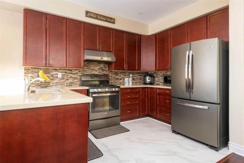 a kitchen with wooden cabinets and a stainless steel refrigerator at Jazzy Home Stay in Mississauga