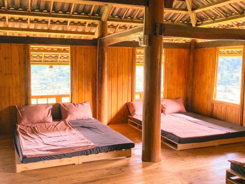 2 camas en una habitación con paredes y ventanas de madera en Vietoutdoors Homestay, en Sa Pa