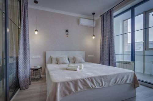 a bedroom with a white bed with a large window at Asaapart Ush-Sunkar 153 in Almaty