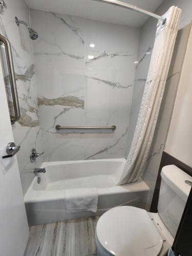 a bathroom with a white tub and a toilet at Travelodge Inn & Suites by Wyndham Fullerton in Fullerton