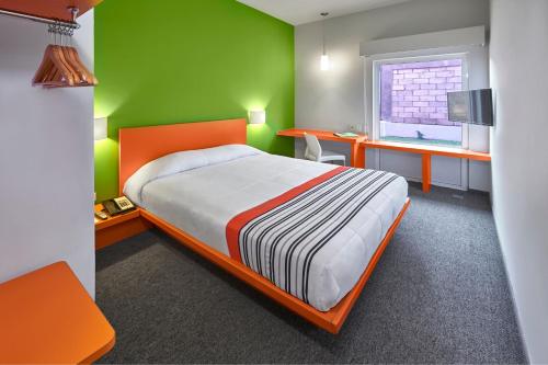 a bedroom with a bed and a green wall at City Express Junior by Marriott Guadalajara Periferico Sur in Guadalajara