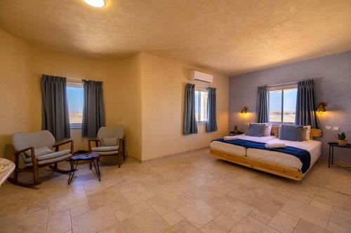 - une chambre avec un lit, des chaises et des fenêtres dans l'établissement Shermans Hotel, à Sde Boqer