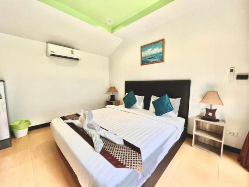 a bedroom with a large white bed with blue pillows at The Shore Samui in Bang Rak Beach