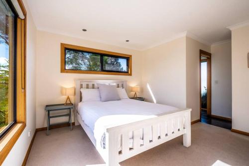 a bedroom with a white bed and a window at Blue Waves in Coles Bay