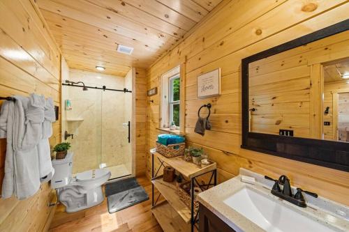 ein Badezimmer mit Toilette, Waschbecken und Spiegel in der Unterkunft LUXURY 4BR Cabin in Gatlinburg with Views Hot Tub with Private Deck Game Room Most Popular Coffee Bar Perfect for Family Getaway Tennis Courts Infant Crib and Karaoke System in Gatlinburg