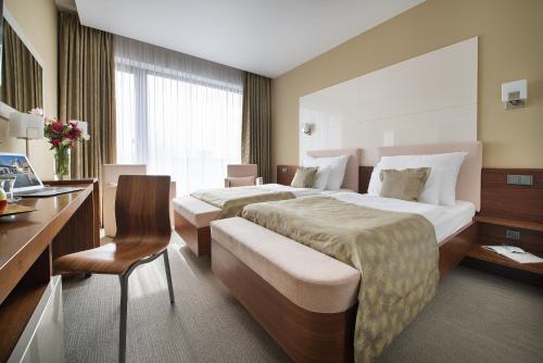 a hotel room with two beds and a desk at Wellness Hotel Diamant in Hluboká nad Vltavou