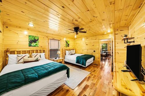 ein Schlafzimmer mit zwei Betten in einer Blockhütte in der Unterkunft LUXURY 4BR Cabin in Gatlinburg with Views Hot Tub with Private Deck Game Room Most Popular Coffee Bar Perfect for Family Getaway Tennis Courts Infant Crib and Karaoke System in Gatlinburg