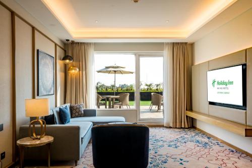 a living room with a couch and a flat screen tv at Holiday Inn Lucknow Airport by IHG in Lucknow