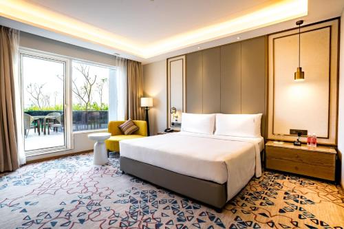 a hotel room with a bed and a large window at Holiday Inn Lucknow Airport by IHG in Lucknow