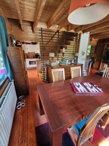 een eetkamer met een houten tafel en een keuken bij Le chalet du Cerf - Chambres d'hôtes in Somme-Leuze