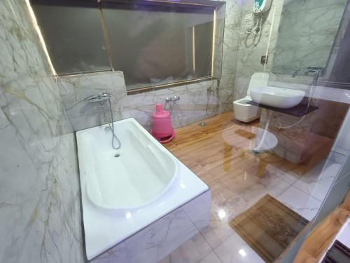 a bathroom with a white tub and a sink at HOTEL ROCK in Anand