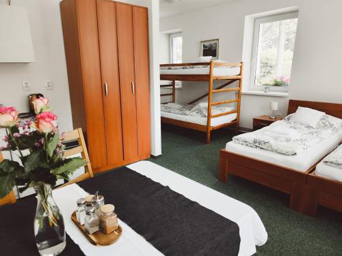 una habitación con 2 camas y una mesa con un jarrón de flores en Ubytování Goliáš, en Krásná Lípa