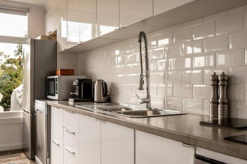 a white kitchen with a sink and a microwave at Elusive Penguin in Bicheno