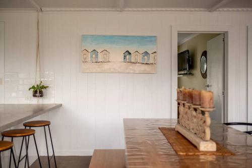 a living room with a painting of houses on the wall at Elusive Penguin in Bicheno
