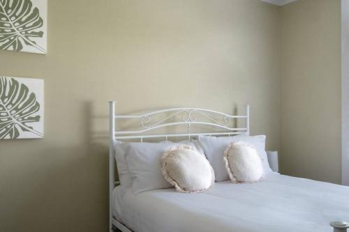 a white bed with two pillows on top of it at Elusive Penguin in Bicheno