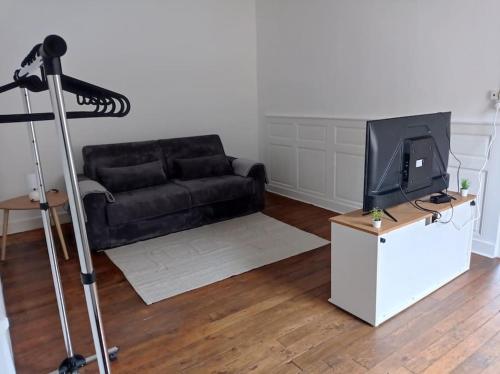 a living room with a black couch and a television at Appartement centre Saulieu in Saulieu