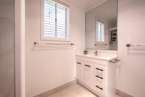a white bathroom with a sink and a mirror at Elusive Penguin in Bicheno