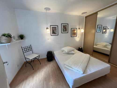 une chambre avec un lit, une chaise et un miroir dans l'établissement Le moulin du château, à Blain