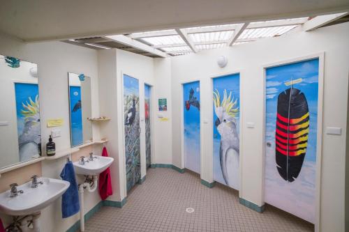 a bathroom with two sinks and a surfboard on the wall at YHA Pittwater Eco, Sydney in Church Point