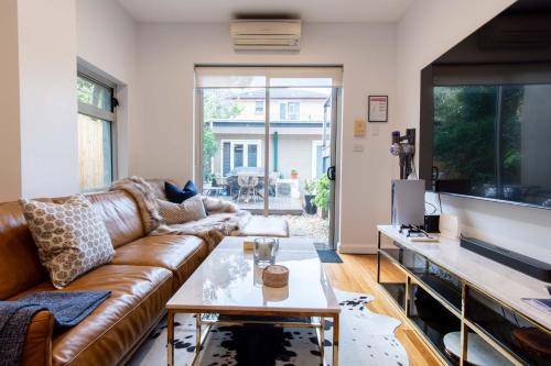 a living room with a brown leather couch and a table at Eggies Nest - Sydney City Apartment in Sydney