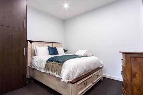 a bedroom with a bed and a wooden dresser at Eggies Nest - Sydney City Apartment in Sydney
