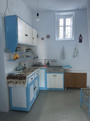 una cucina blu con armadi bianchi e lavandino di Cycladic house with amazing view in Potamia village a Dhió Kkhoriá