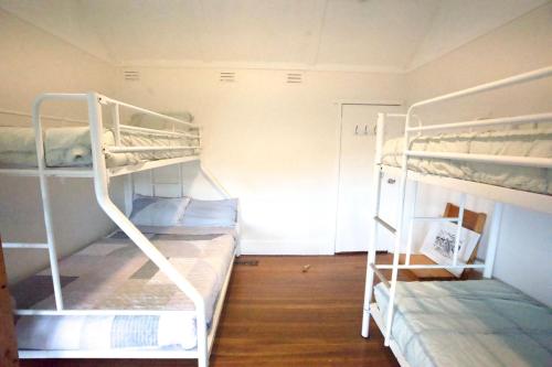 two bunk beds in a small room with wooden floors at YHA Pittwater Eco, Sydney in Church Point