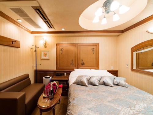 a bedroom with a bed and a couch at Restay Puchi Nagasaki Club (Adult Only) in Nagasaki