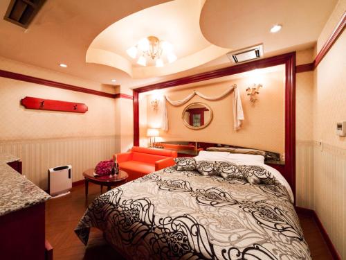 a hotel room with a bed and a red couch at Restay Puchi Nagasaki Club (Adult Only) in Nagasaki