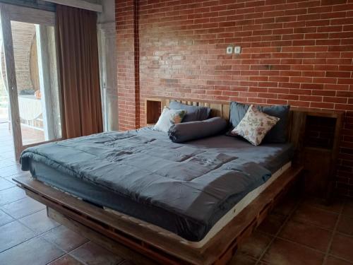 a bed in a room with a brick wall at Pondok isoke bunggalow in Banyuwangi