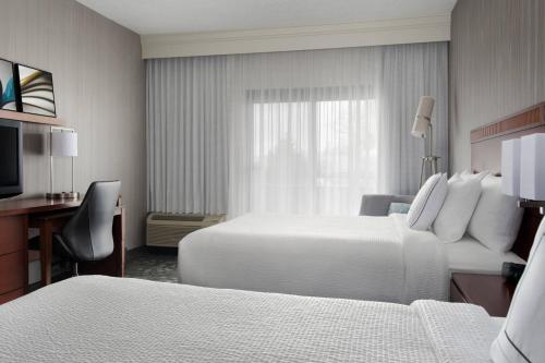 um quarto de hotel com duas camas e uma secretária em Courtyard Syracuse Carrier Circle em East Syracuse