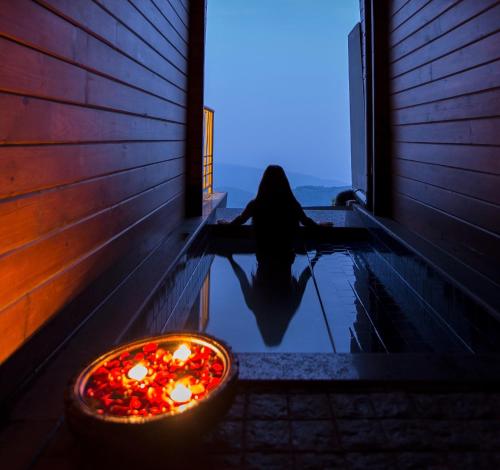 a woman sitting in a pool of water with candles at Polo Orchid Resort Cherrapunjee in Cherrapunji