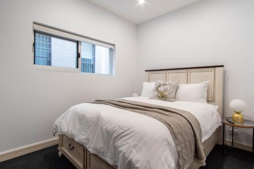 a white bedroom with a large bed with a window at Eggie's Nest - Luxury City Apartment in Sydney