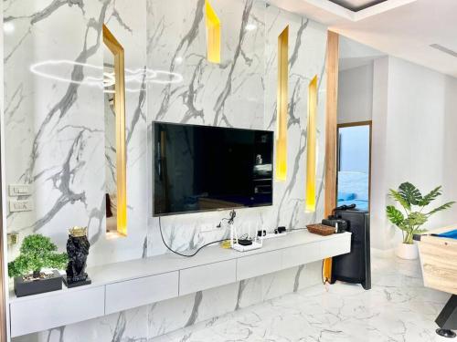 a living room with a television on a white wall at Napa Pool Villa Pattaya in Nong Prue