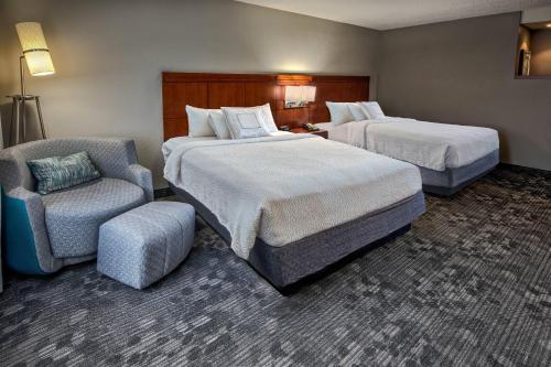una habitación de hotel con 2 camas y una silla en Courtyard by Marriott Troy, en Troy