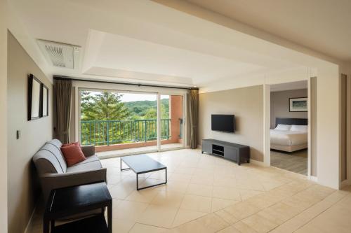 Oak Valley Resort في ونجو: غرفة معيشة بها أريكة وتلفزيون وسرير