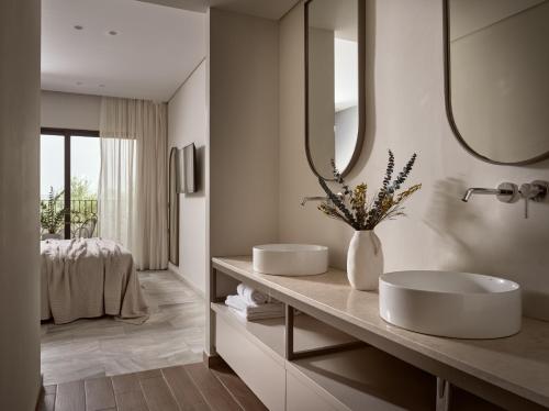 Baño con 2 lavabos y espejo en Hotel Pallas, en Laganas
